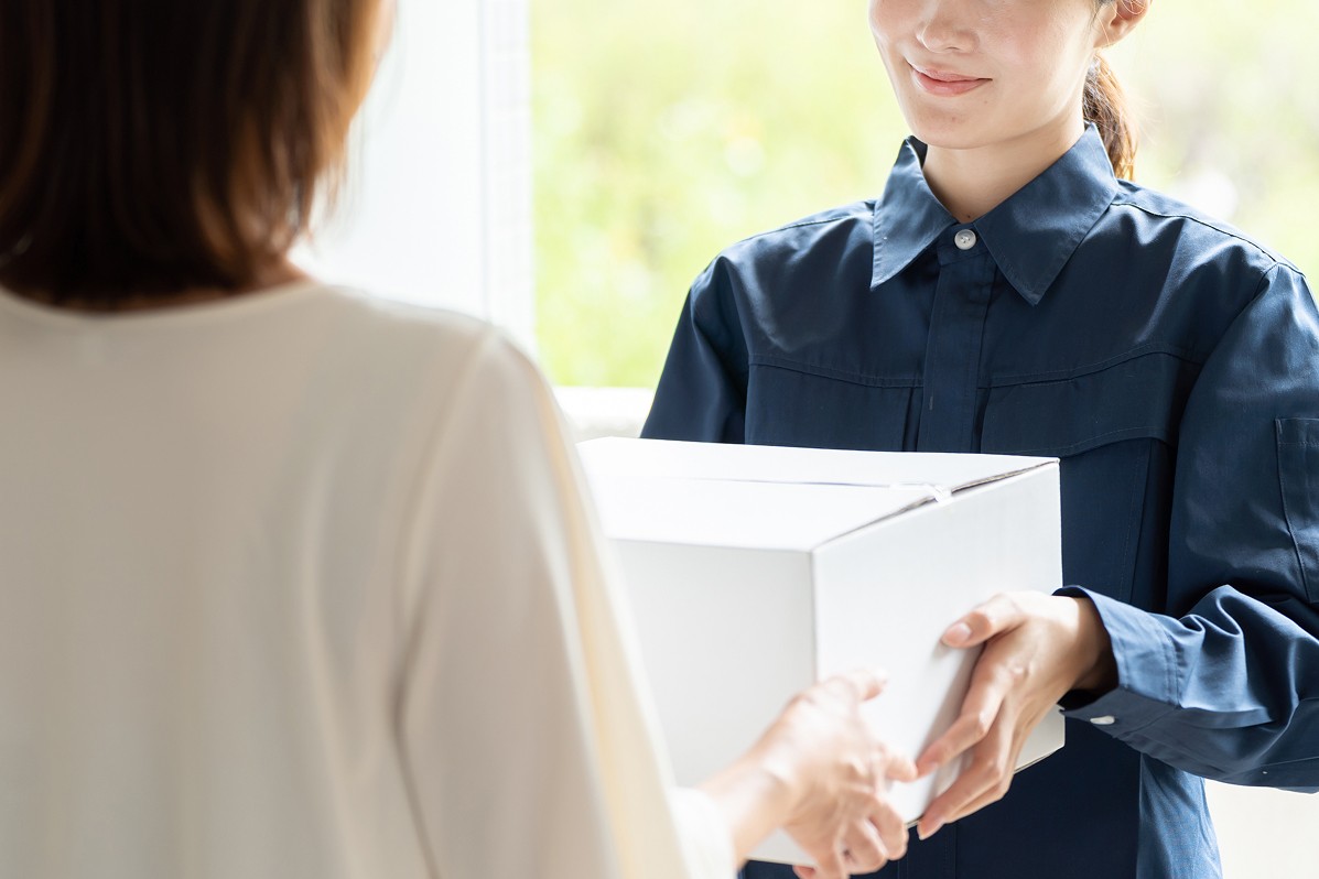 宅配業者から荷物を受け取る女性。