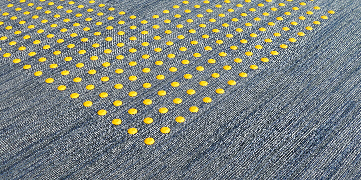 床面に敷かれている、黄色い突起が並んだ視覚障害者用の誘導ブロック。