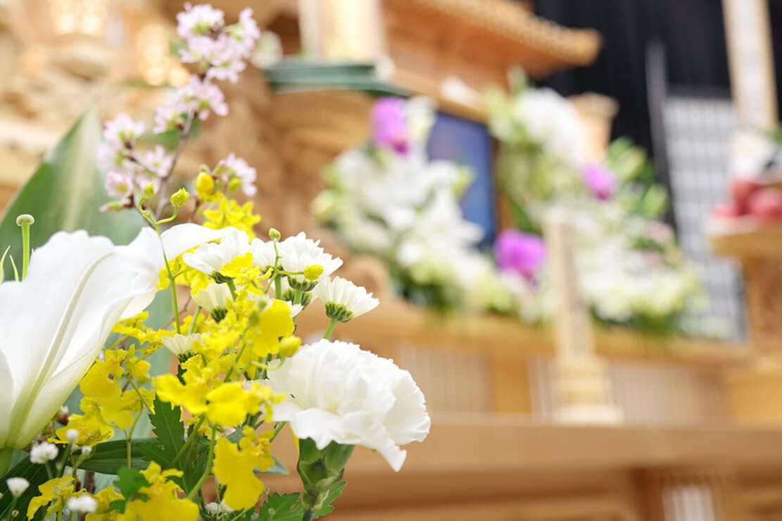 白や黄色の生花で美しく装飾された、宴会場の祭壇・供花