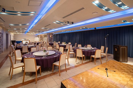 グリーンのテーブルクロスと装花が爽やかな、光が差し込む明るい宴会会場