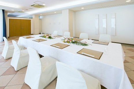 開放的なガラス窓に面した、白で統一された清潔感のある円卓の会食会場